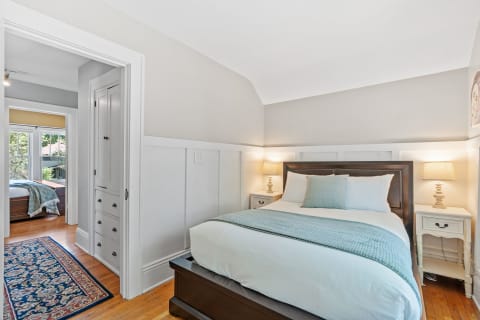 A cozy bedroom featuring a queen-sized bed, warm lighting, and classic decor elements.