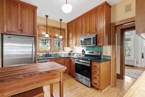 Modern kitchen with wooden cabinets, granite countertops, and stainless steel appliances.