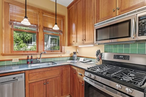 A well-designed kitchen featuring wood cabinets, green tiled backsplash, and modern appliances.