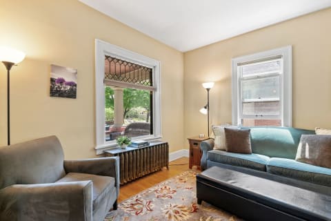 Cozy living room featuring teal sofa, gray armchair, and warm lighting.