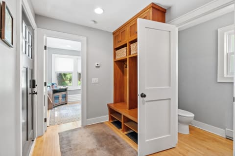 A mudroom with a wooden bench, storage, and an adjacent room visible.