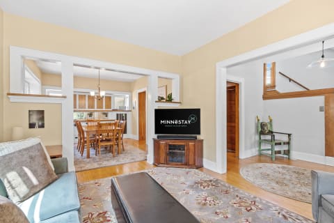 Cozy living room connected to a dining space, with warm tones and wooden accents.