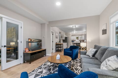 Bright and inviting living room featuring a gray sofa, blue chairs, and a television on a black console.