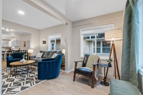 Contemporary living room featuring blue armchairs, a grey sofa, and a wooden coffee table.