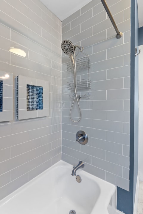 Modern shower area featuring gray tiles and blue mosaic accents.
