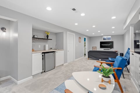 A modern basement living space featuring a kitchenette, seating area, and modern decor.