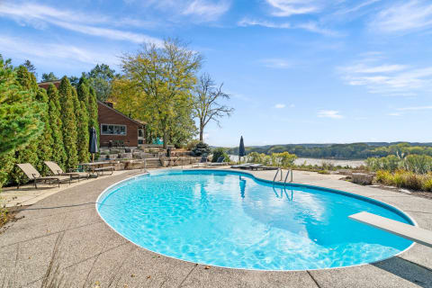 A backyard with a swimming pool, lounge chairs, and a river view.