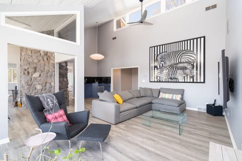 Modern living room with gray sectional sofa, zebra artwork, and stone wall.