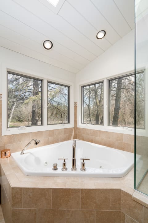 Corner jacuzzi tub with nature views in a modern bathroom.
