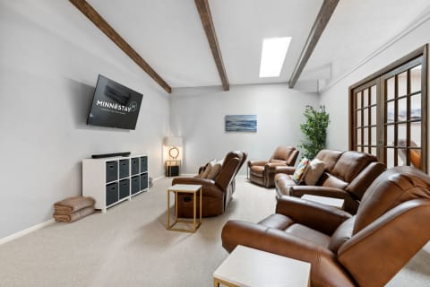 Cozy living room featuring brown leather recliners, a wall-mounted TV, and ambient lighting.