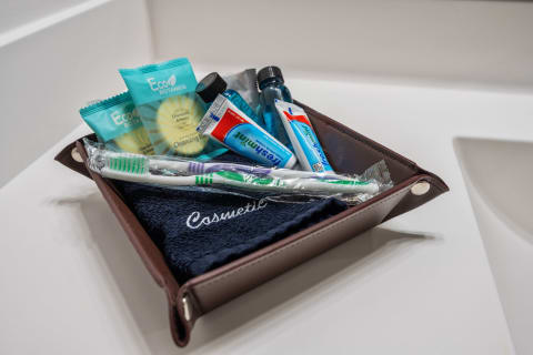 A bathroom accessory holder with cleansing bars, toothpaste, a toothbrush, and a towel.