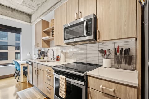 Interior of a modern kitchen featuring light wood cabinets, stainless steel appliances, and a cozy breakfast nook.