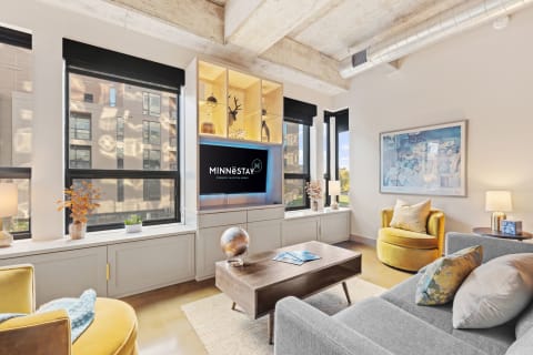 Modern living room featuring a gray sofa, yellow accent chair, and large windows.