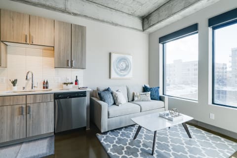 A modern studio apartment featuring a compact kitchen and cozy living area with large windows.