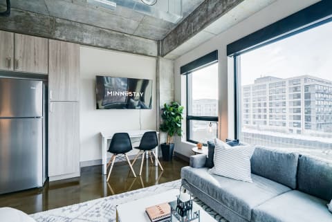 Modern living room with a gray sofa, two black chairs, and large windows.