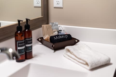 Neat bathroom countertop with hand wash, lotion, and a makeup towel.