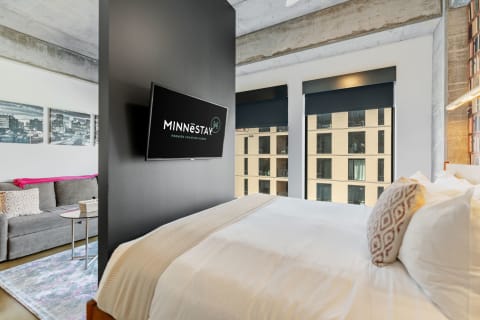 Contemporary hotel room featuring a bed, television, and seating area.