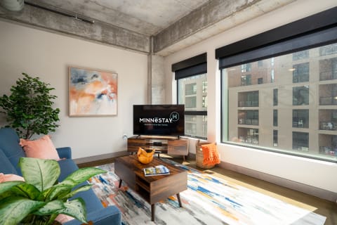 Contemporary living room with blue sofa, abstract art, and large windows.