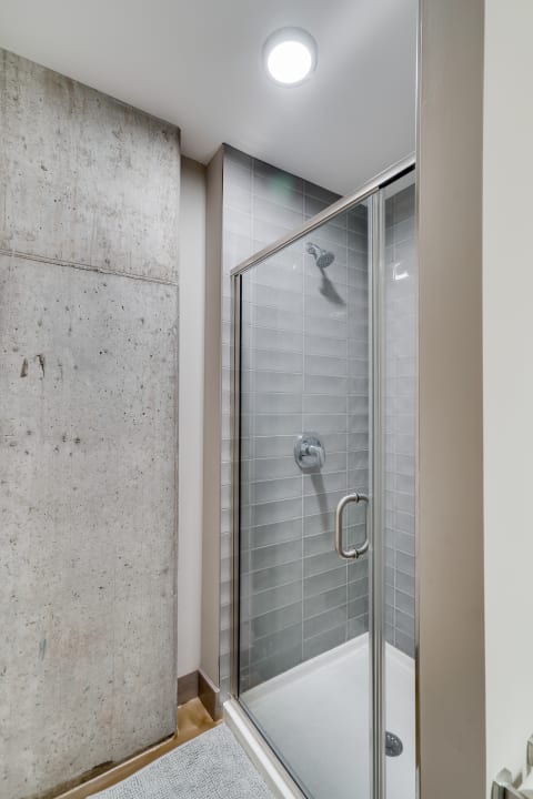 A contemporary shower with glass enclosure and gray wall tiles.