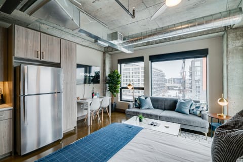 Stylish modern studio apartment featuring a kitchen, living area, and city views.