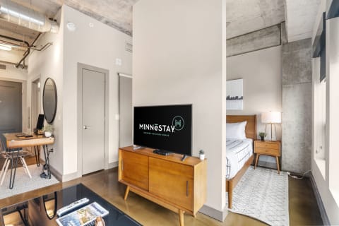 Contemporary living area with a bedroom visible in the background, showcasing modern furniture and industrial design elements.