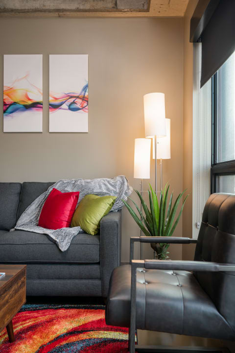 Modern living room with gray sofa, abstract art, and colorful rug.