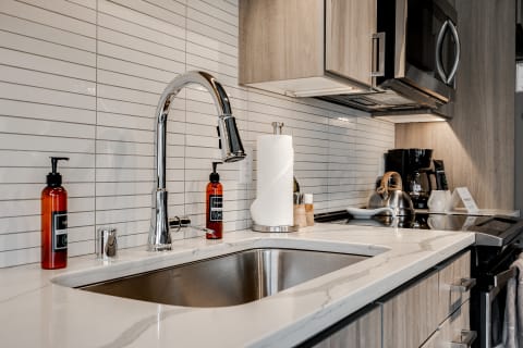 Modern kitchen countertop featuring a stainless steel sink, sleek faucet, and stylish appliances.