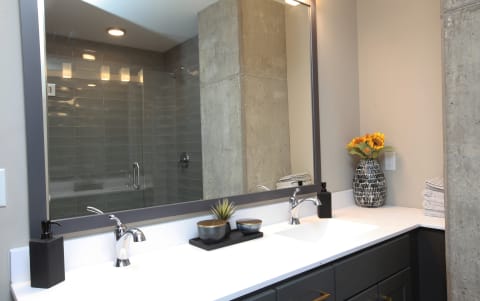 Modern bathroom featuring a sleek vanity, decorative items, and a glass shower.
