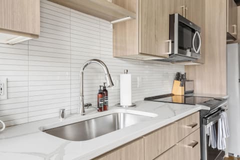 Contemporary kitchen features including a stainless steel sink, marble countertop, and wooden cabinets.