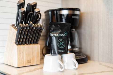 Modern kitchen countertop with a knife block, coffee cups, and coffee package.