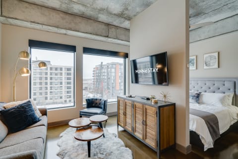 Interior of a contemporary studio apartment featuring a sofa, coffee tables, and a bed.