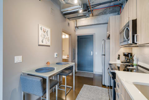 Interior view of a modern kitchen featuring a dining table, gray walls, and stainless steel appliances.