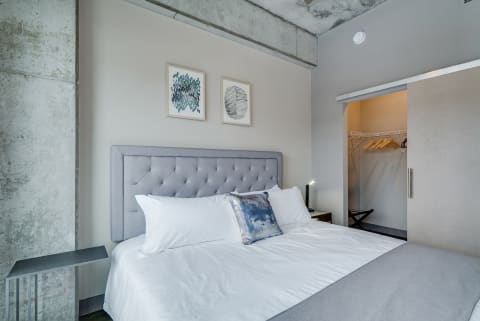 Modern bedroom with gray headboard and minimalist decor.