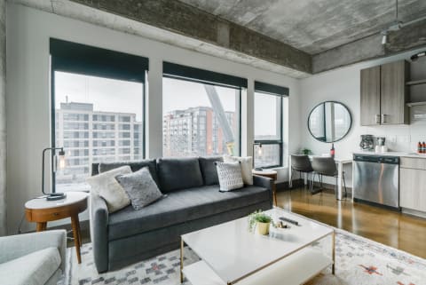 Stylish modern living room with gray sofa, wooden accents, and large windows.
