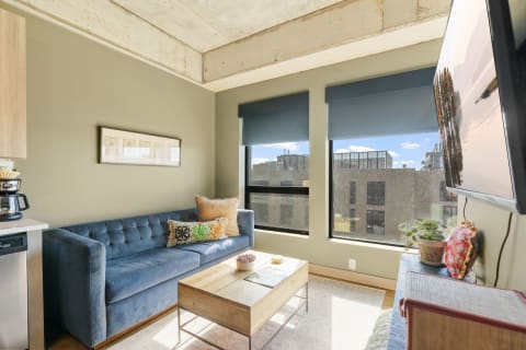 Modern living room with a blue couch, coffee table, and large windows.