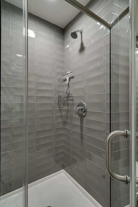 Modern shower enclosure with gray tiles and chrome fixtures.
