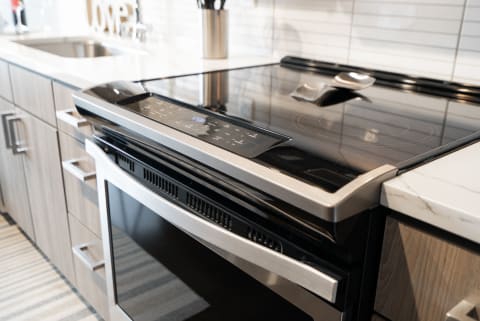 A close-up view of a contemporary kitchen stove featuring a glass top and stainless steel design.