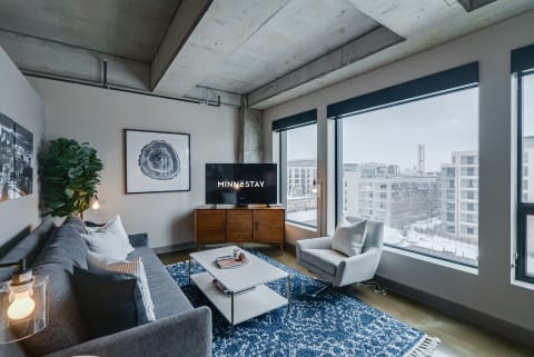 Modern living room with gray sofa, coffee table, and windows showcasing a snowy view.