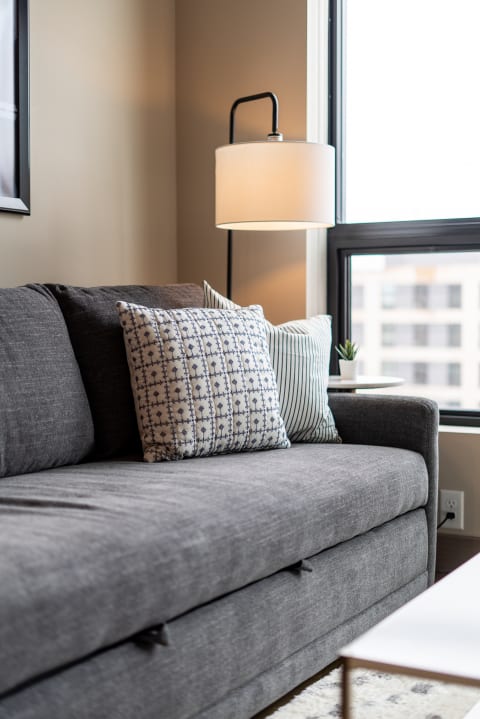 Cozy gray sofa with pillows and a floor lamp in a living room corner.