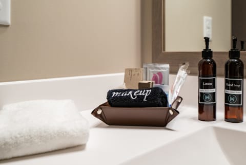 Neatly arranged bathroom countertop with a towel, a brown container of personal care items, and bottles of lotion and hand soap.