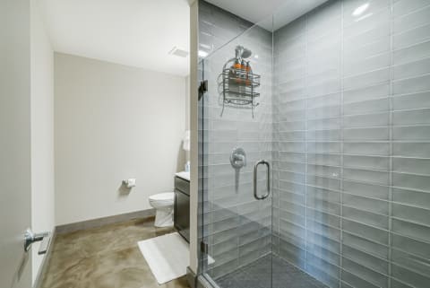 Interior view of a contemporary bathroom with a glass shower and dark vanity.