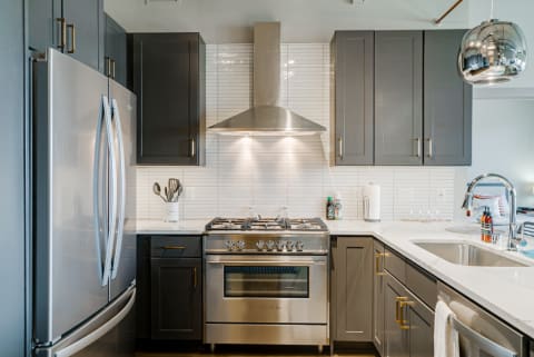 Modern kitchen featuring gray cabinets, stainless steel appliances, and white countertops.