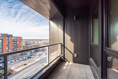 Modern balcony with a city view under a cloudy sky.
