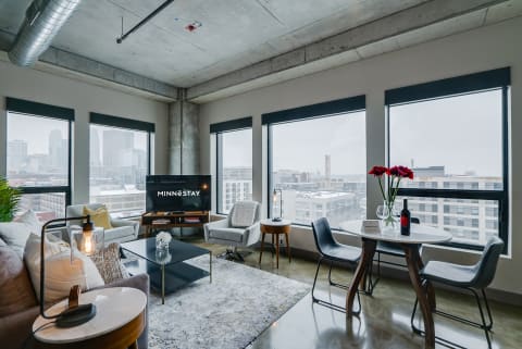 Bright modern living room with city views, decorated with a cozy sofa and dining table.