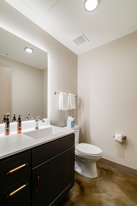 A modern bathroom featuring a dark cabinet, white countertop, and neatly arranged toiletries.