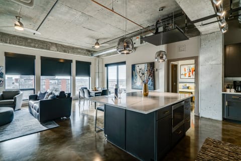 A modern kitchen-living space with marble island and contemporary furniture.