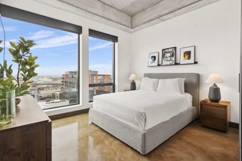 Modern bedroom featuring large windows, a comfortable bed, and stylish decor.