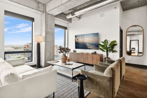 Stylish modern living room featuring large windows, contemporary furniture, and industrial decor.