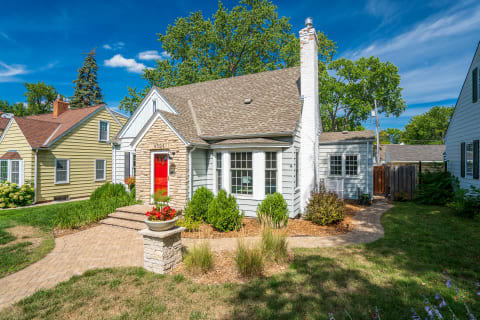 A residential house featuring a red door and surrounded by lush greenery.
