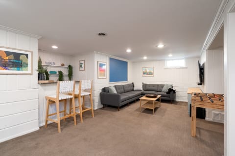 Contemporary basement living room featuring a sectional sofa, bar area, and foosball table.